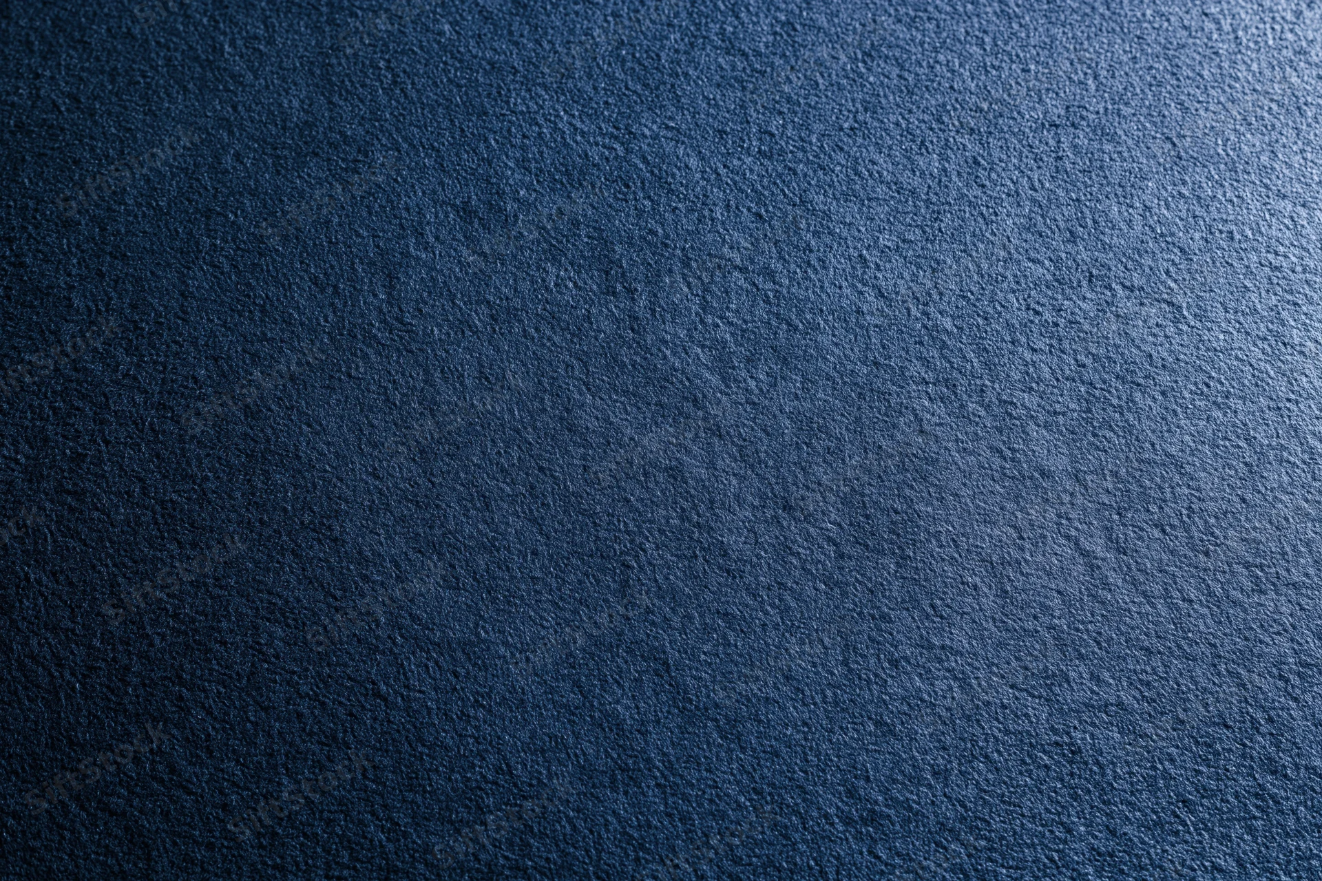 Close-up of deep navy blue suede fabric surface with visible texture and subtle gradient lighting