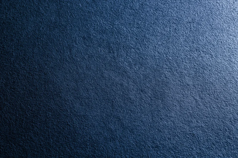 Close-up of deep navy blue suede fabric surface with visible texture and subtle gradient lighting