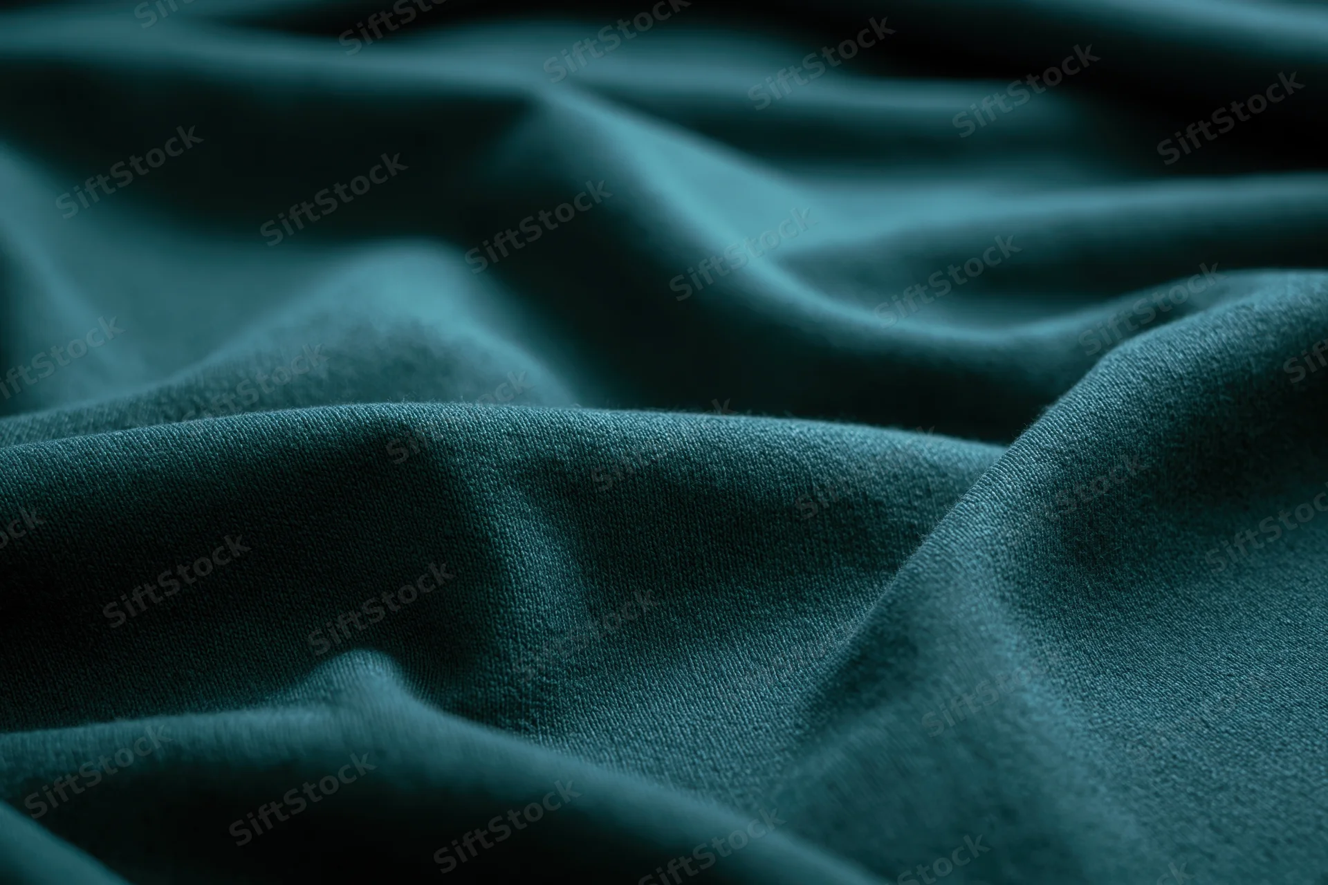 Close-up of deep teal-green fabric with soft folds and texture filling the frame