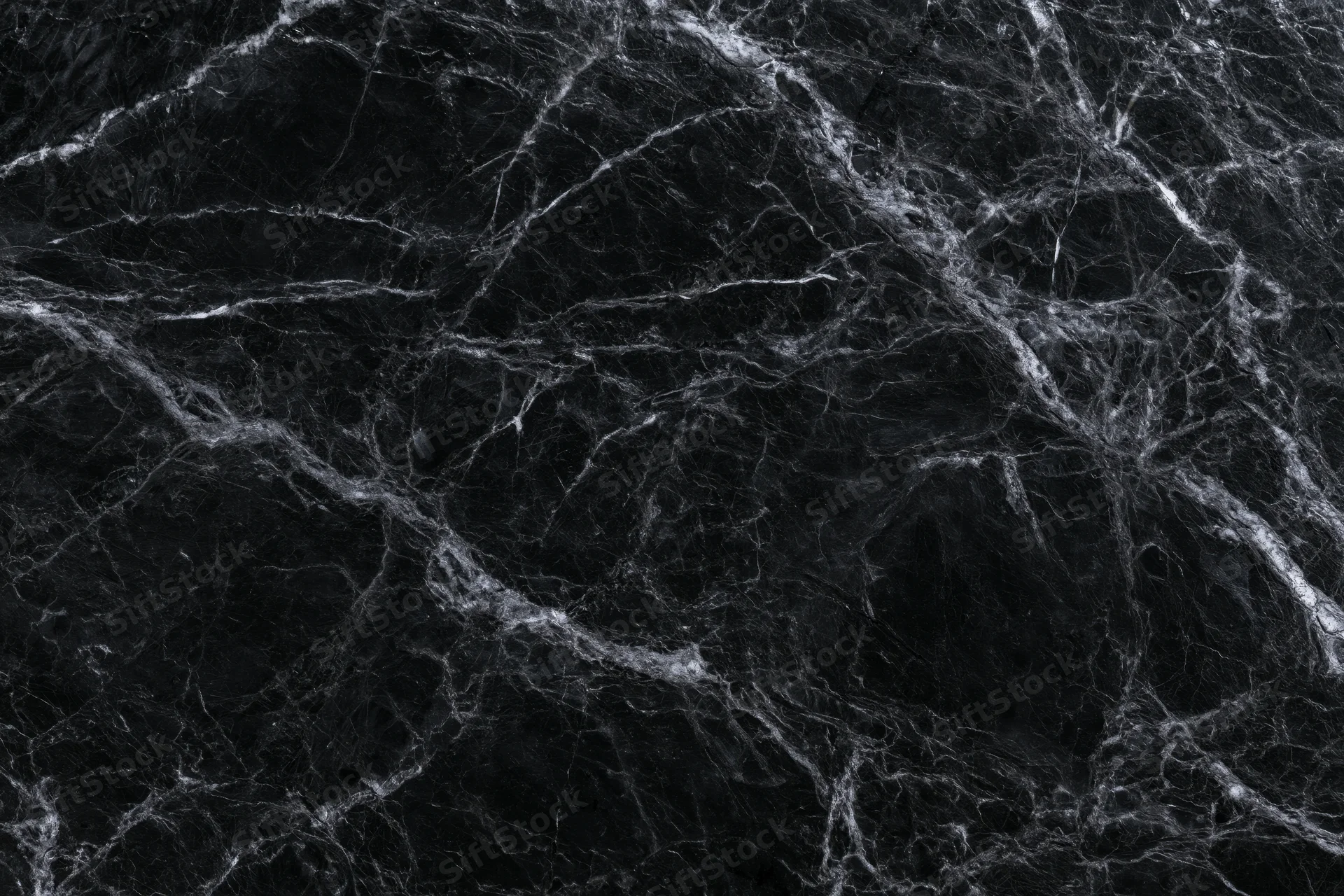 Close-up of polished black marble surface with white veining filling the frame