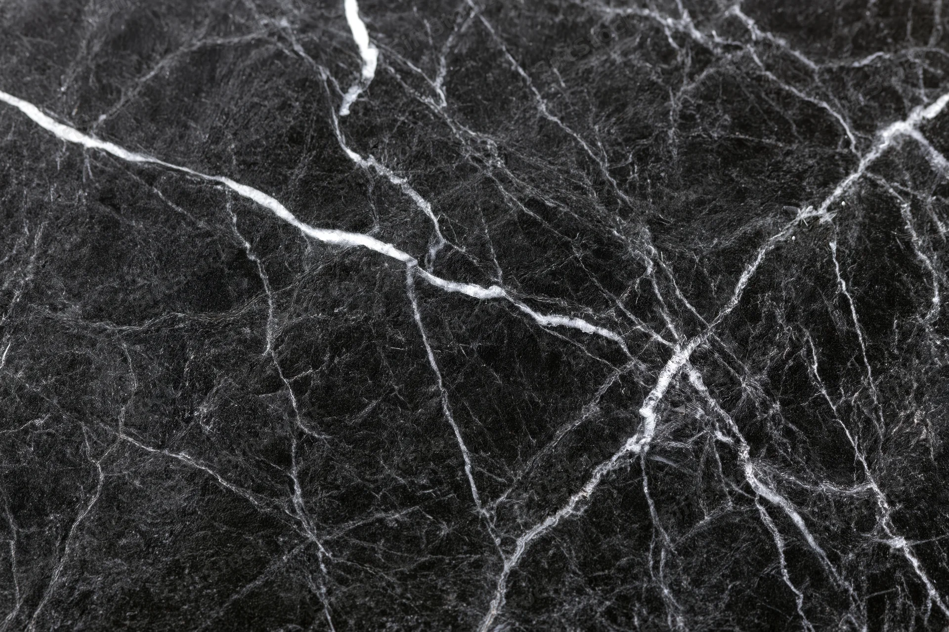 Close-up of polished black marble surface with white veining filling the frame