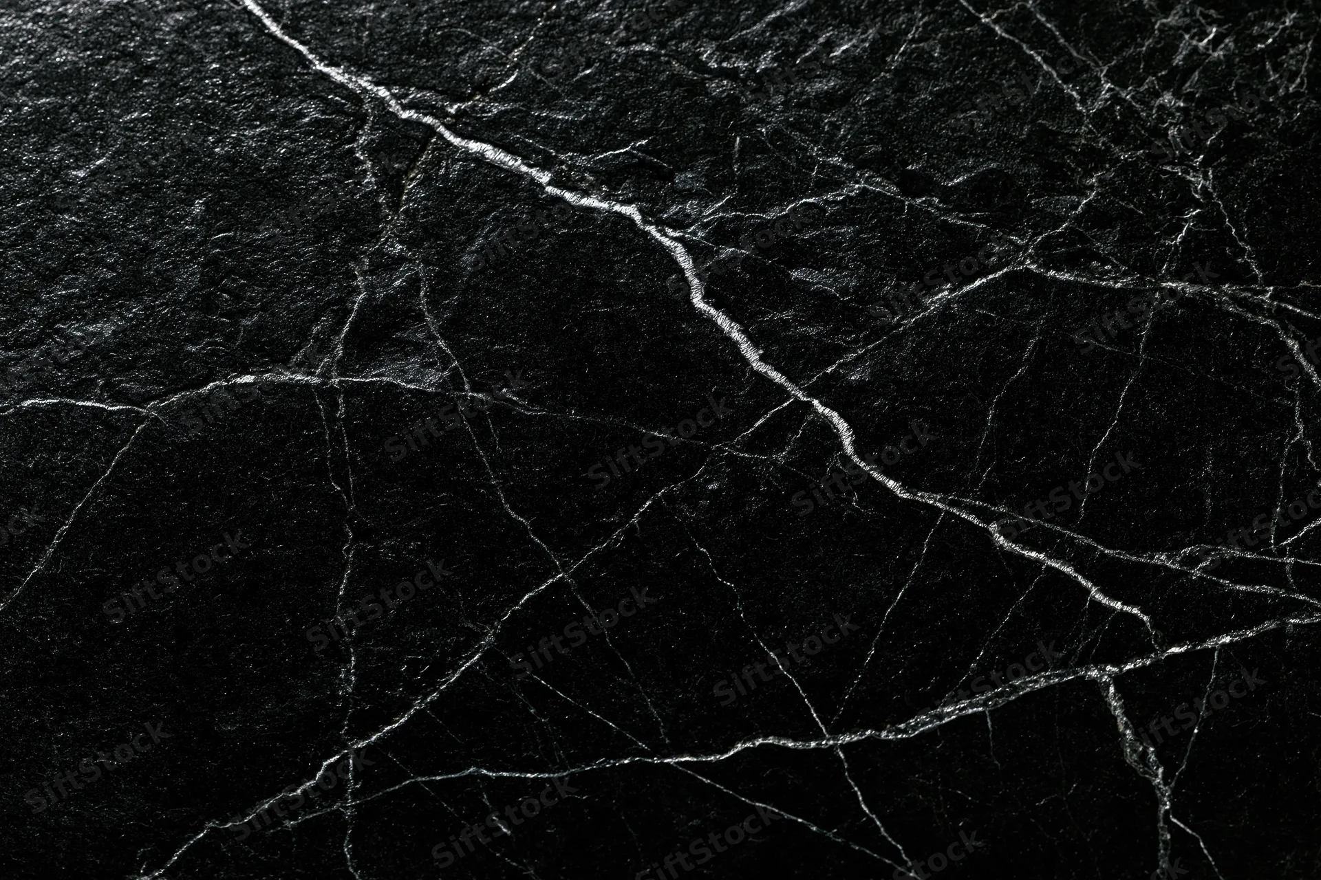 Close-up of polished black marble surface with white veining filling the frame