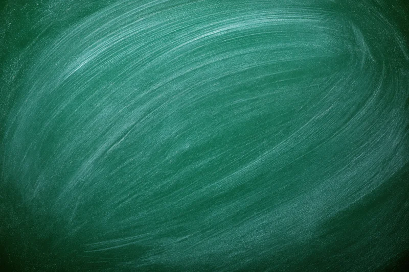 Close-up of a smudged green chalkboard surface with white chalk marks forming a swirling pattern