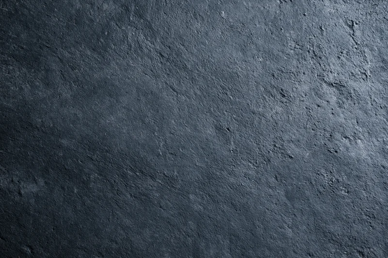 Close-up of dark charcoal concrete wall surface with rough texture and subtle shadows