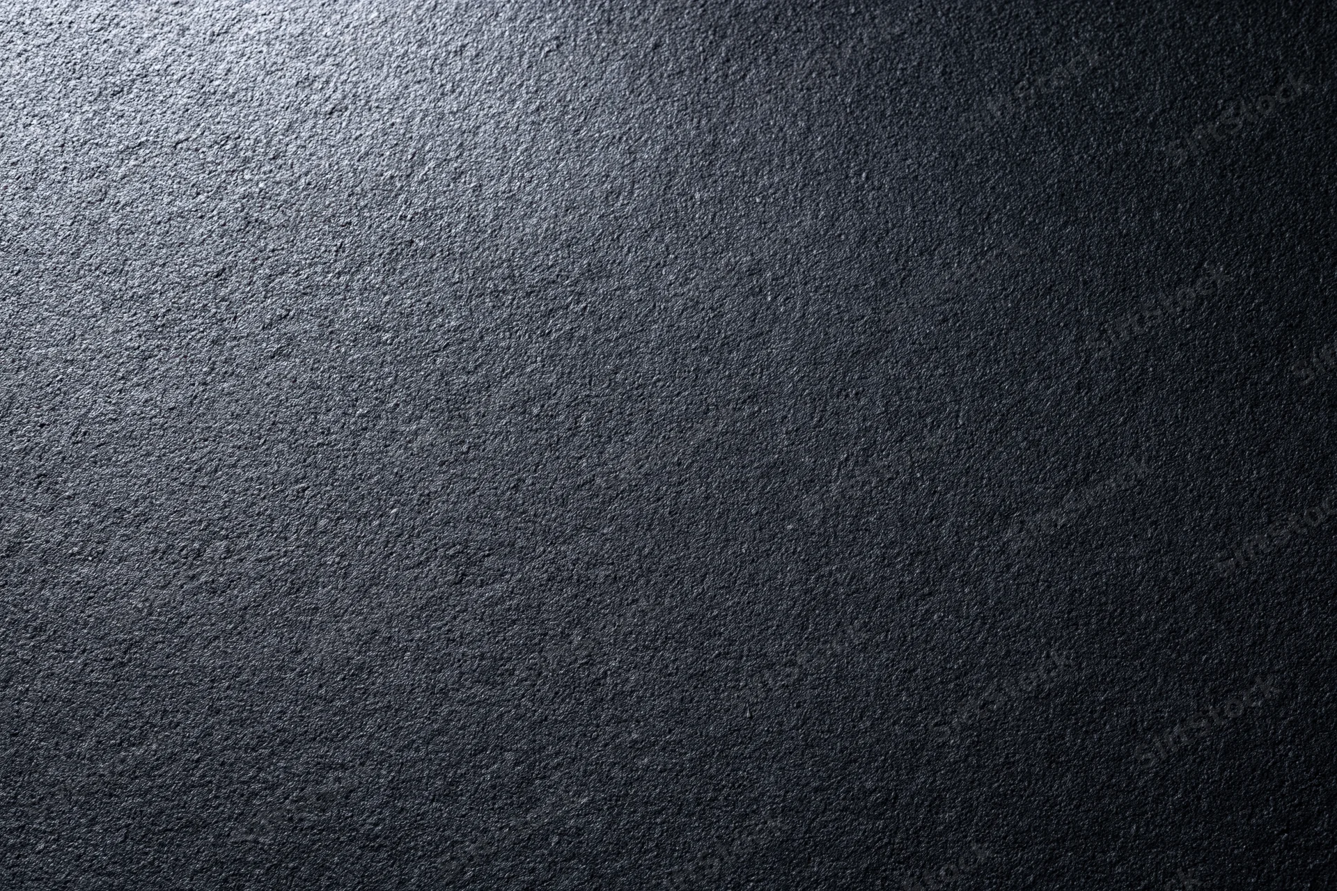 Close-up of dark charcoal matte wall surface with textured grain and gradient lighting