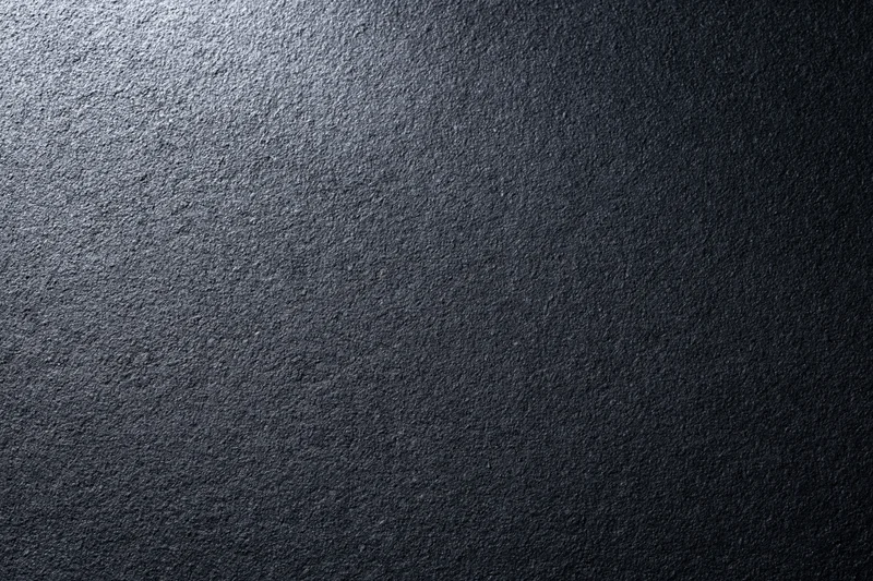 Close-up of dark charcoal matte wall surface with textured grain and gradient lighting