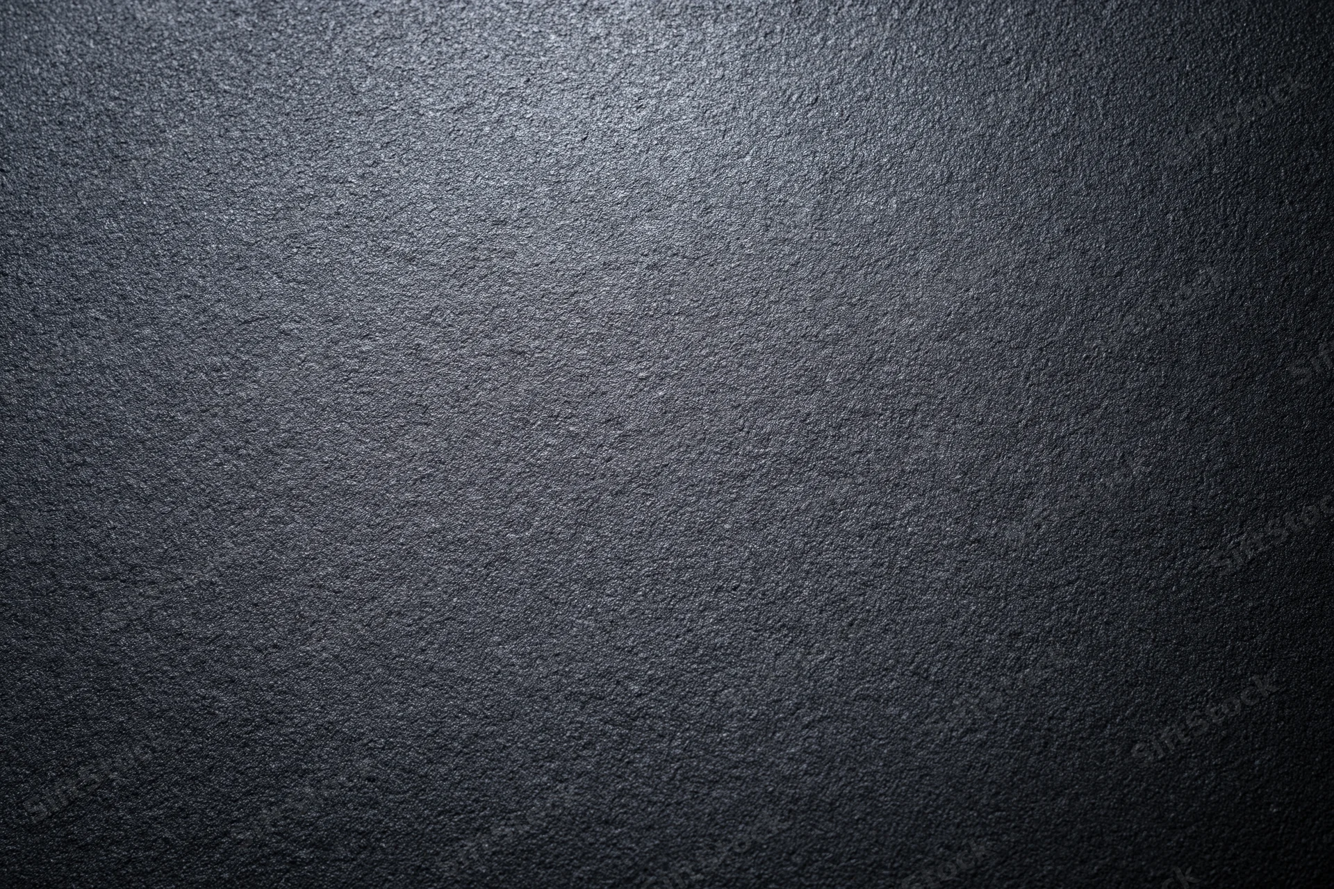 Close-up of dark charcoal matte wall surface with textured grain and subtle light gradient