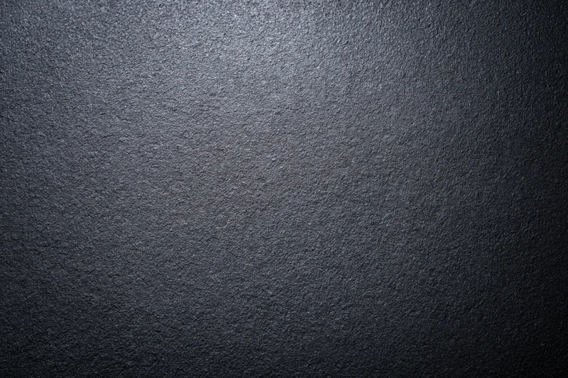 Close-up of dark charcoal matte wall surface with textured grain and subtle light gradient