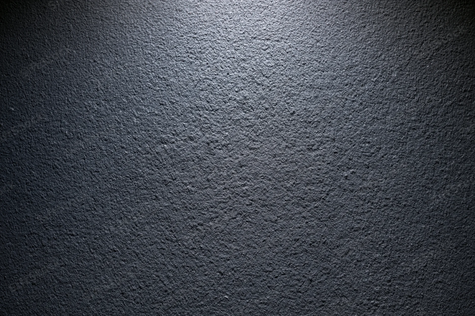 Close-up of dark charcoal matte wall surface with rough texture and spotlight effect