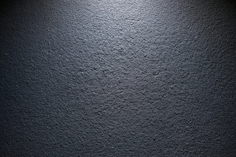Close-up of dark charcoal matte wall surface with rough texture and spotlight effect
