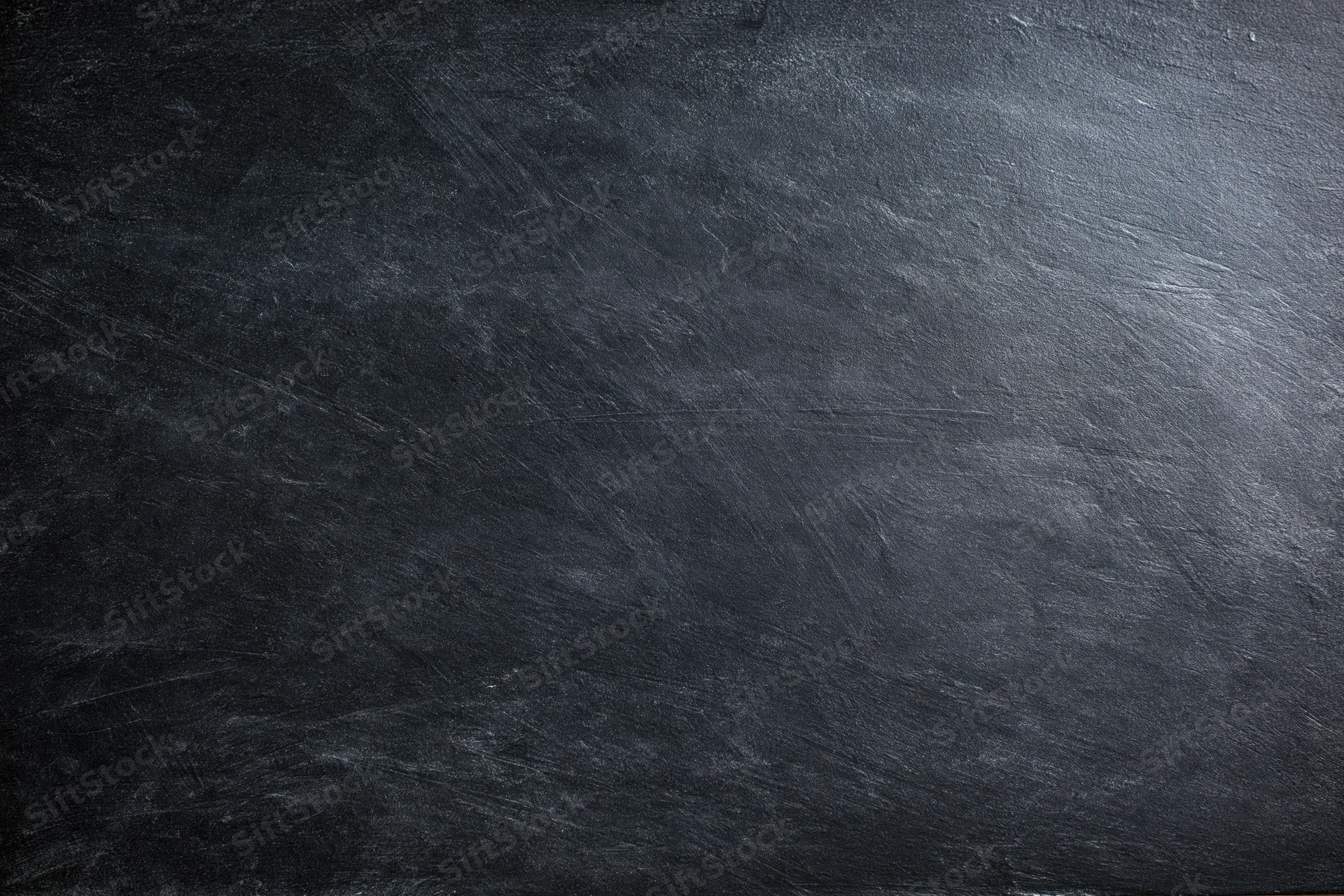 Close-up of dark textured slate surface with natural grain and scratches