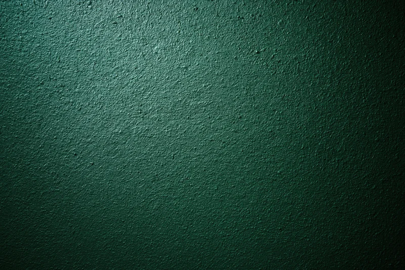 Close-up of deep forest green textured wall surface with rough matte finish and subtle gradient lighting