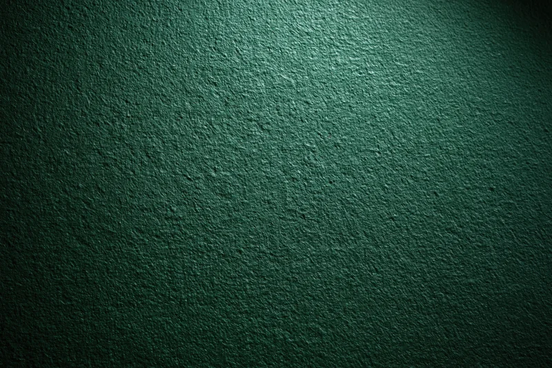 Close-up of deep forest green textured wall surface with spotlight gradient and rough concrete texture