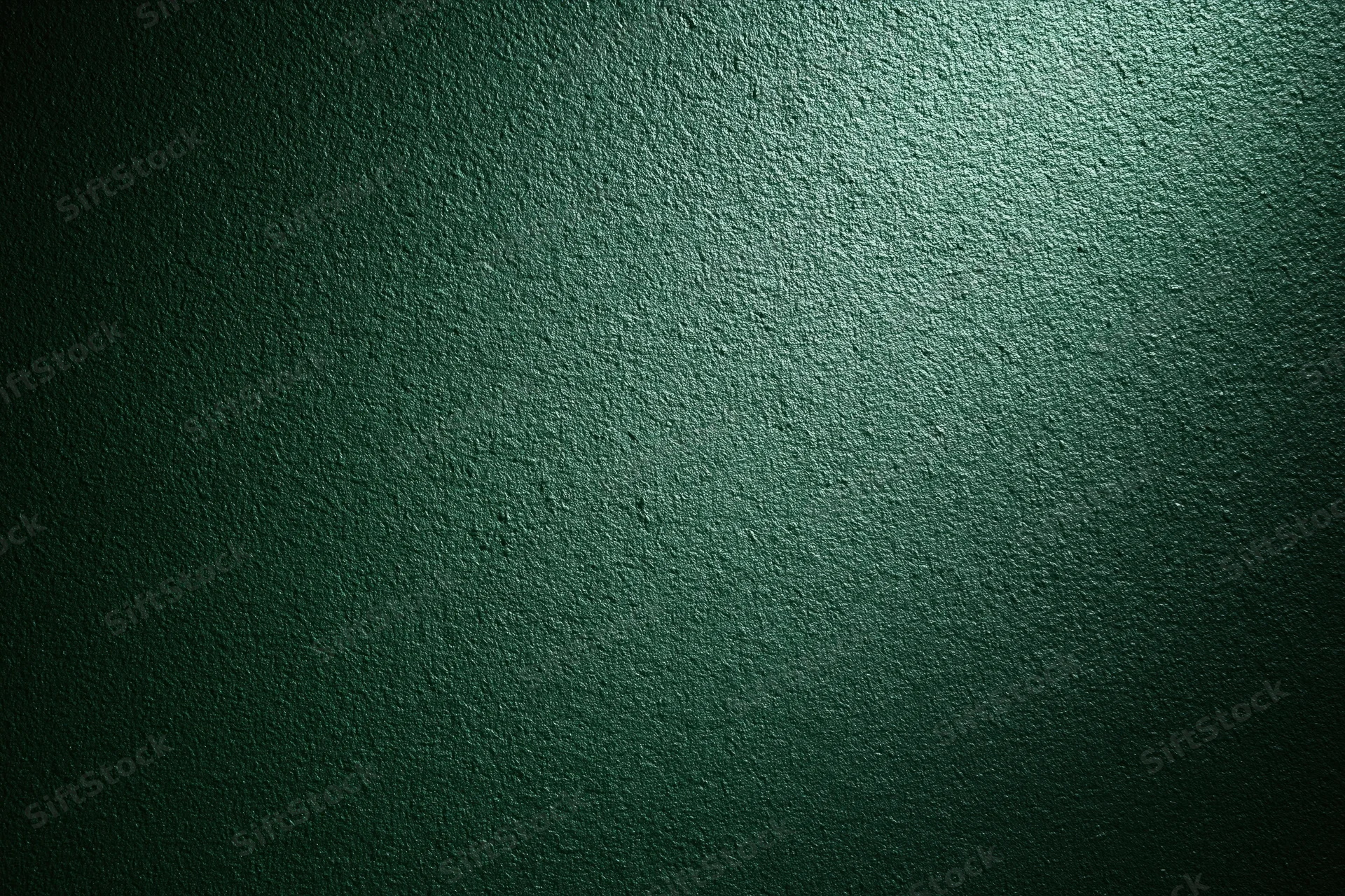 Close-up of a deep forest green textured wall surface with spotlight lighting and vignette effect