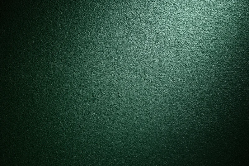 Close-up of a deep forest green textured wall surface with spotlight lighting and vignette effect