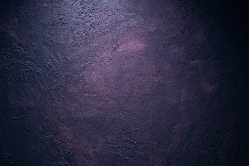 Close-up of rough plastered wall surface with dark purple tones and textured finish