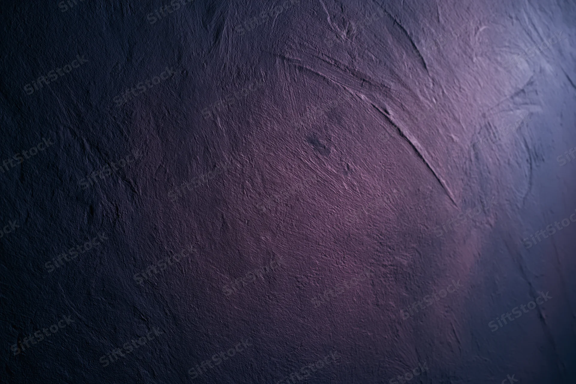 Close-up of rough plastered wall surface with purple and blue gradient lighting