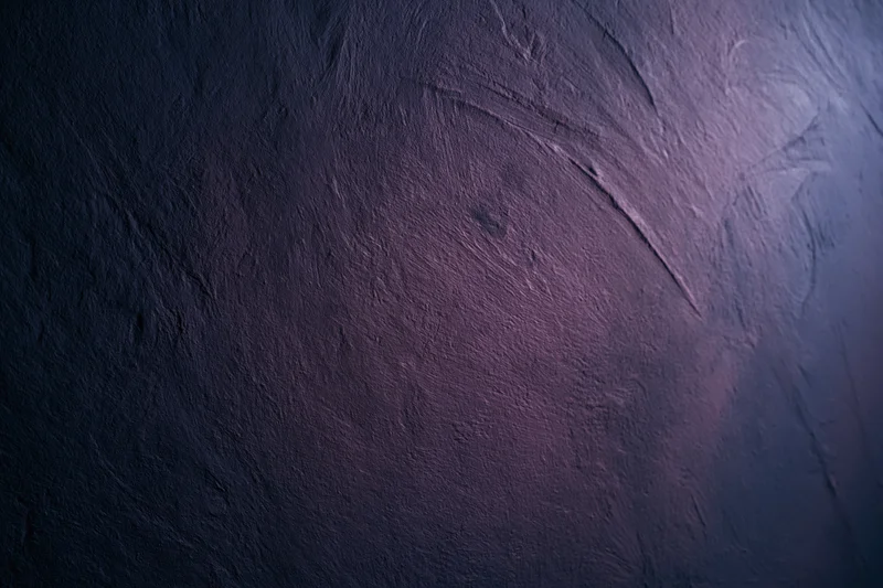 Close-up of rough plastered wall surface with purple and blue gradient lighting