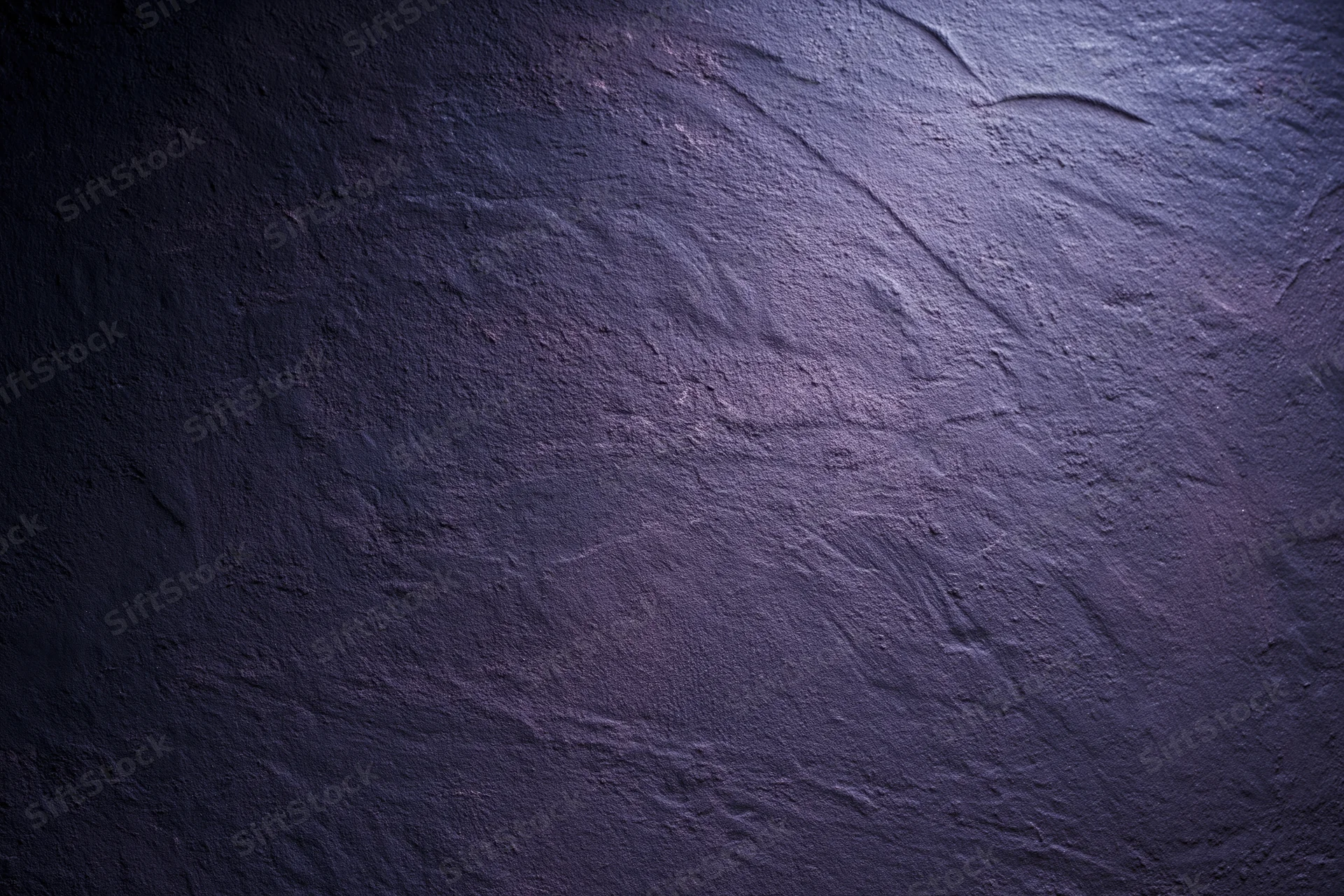 Close-up of rough plastered wall surface with dark purple and blue tones