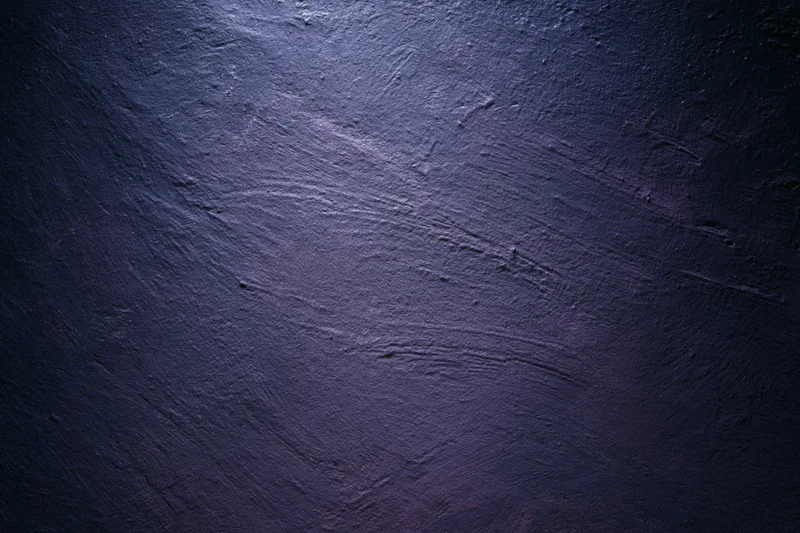 Close-up of rough plastered wall surface with dark blue and purple tones