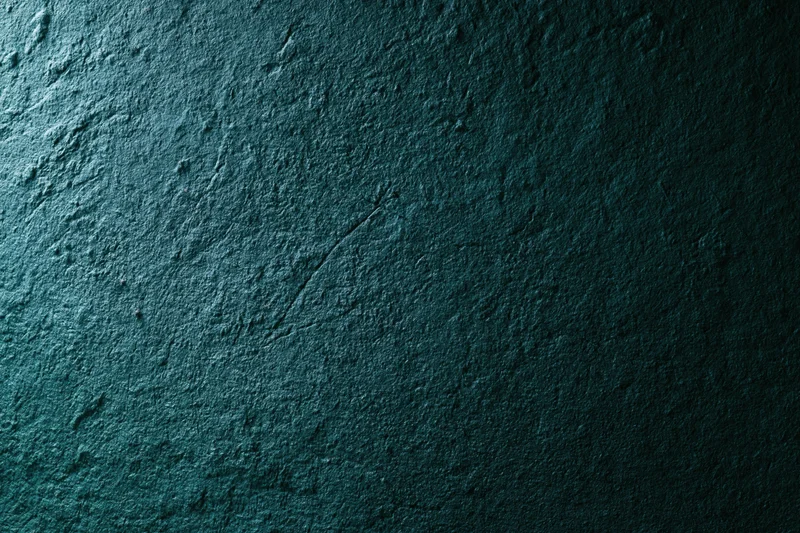 Close-up of rough textured wall surface in dark teal tones with visible cracks and uneven texture