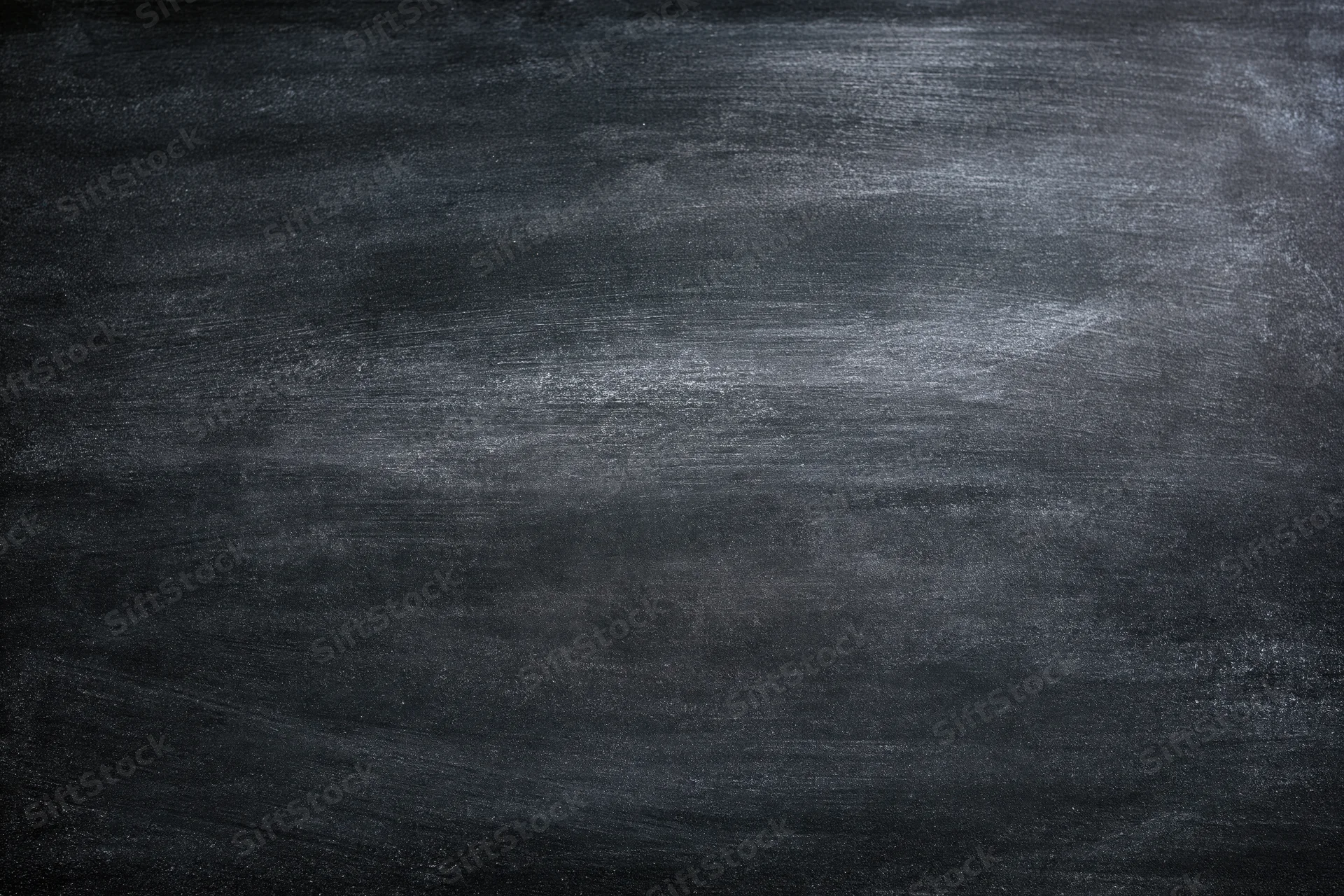 Close-up of a worn chalkboard surface with smudged residue and erased marks