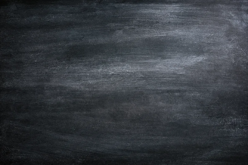 Close-up of a worn chalkboard surface with smudged residue and erased marks