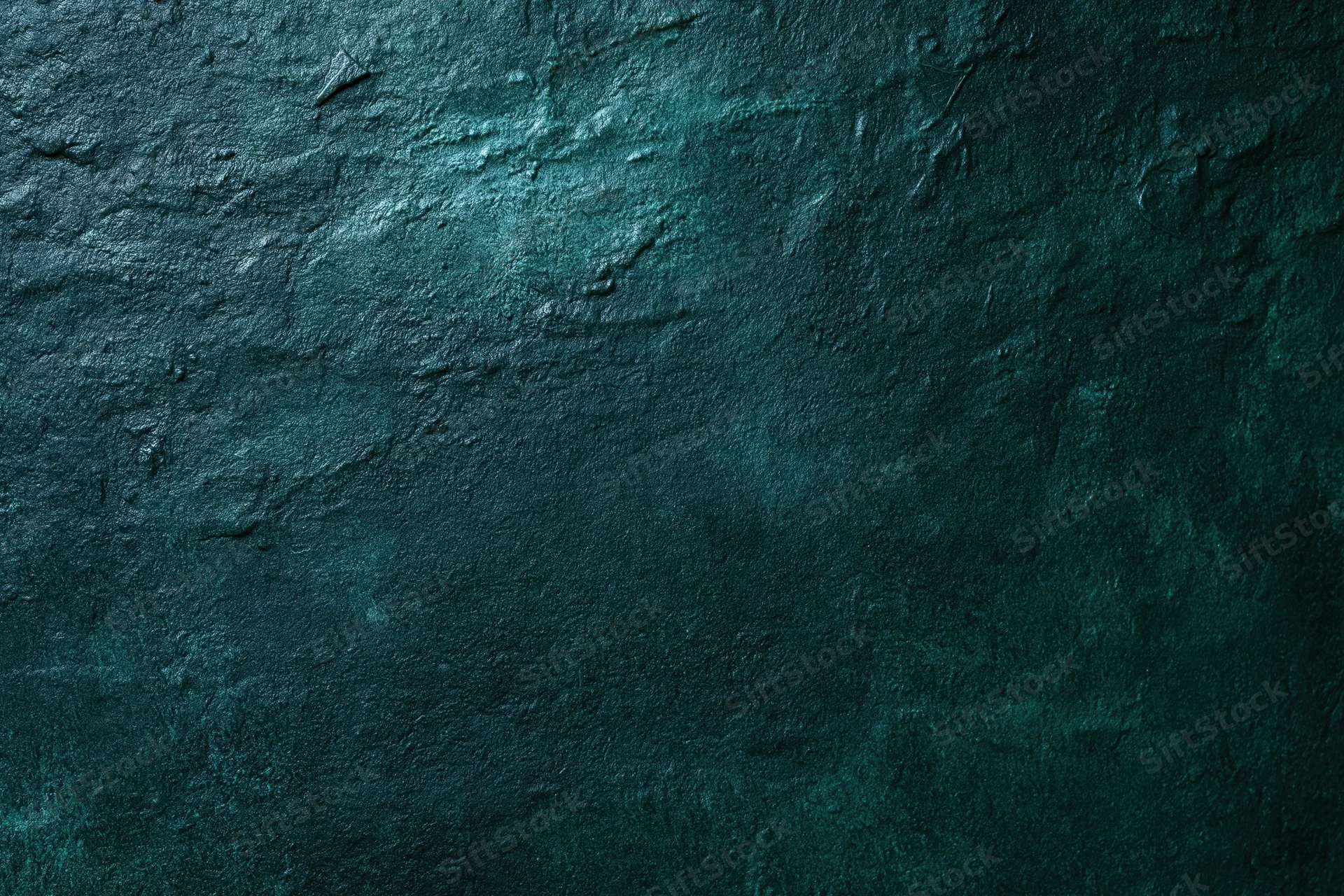 Close-up of a dark teal aged concrete wall surface with rough texture and weathered cracks