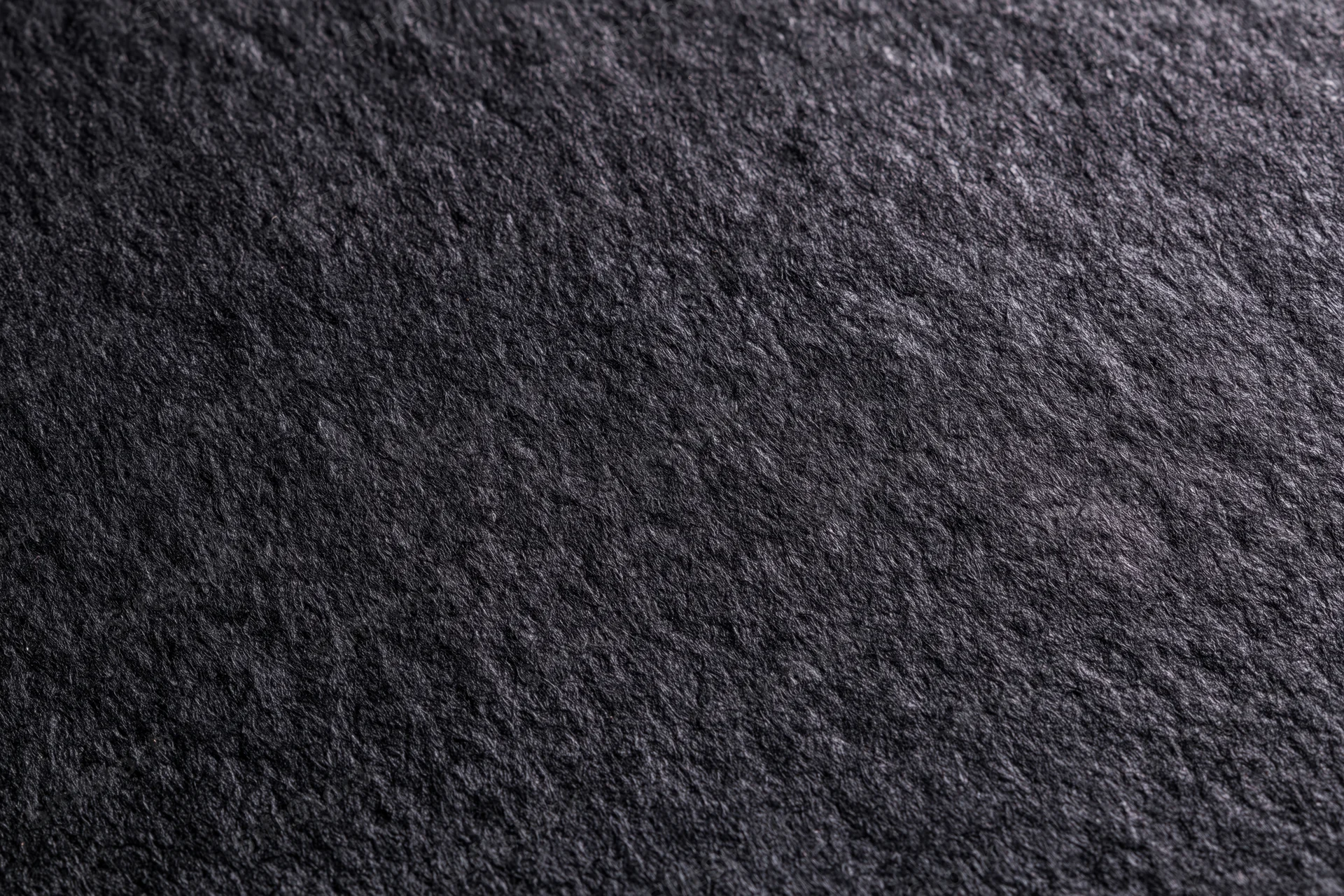 Close-up of dark black textured paper surface filling the frame