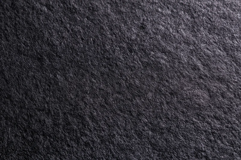 Close-up of dark black textured paper surface filling the frame