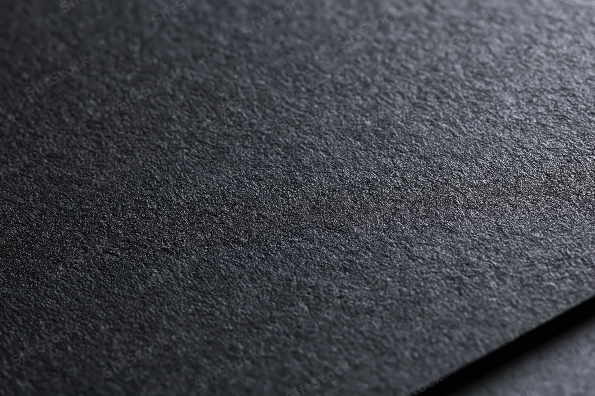 Close-up of dark black textured paper surface with visible grain and matte finish