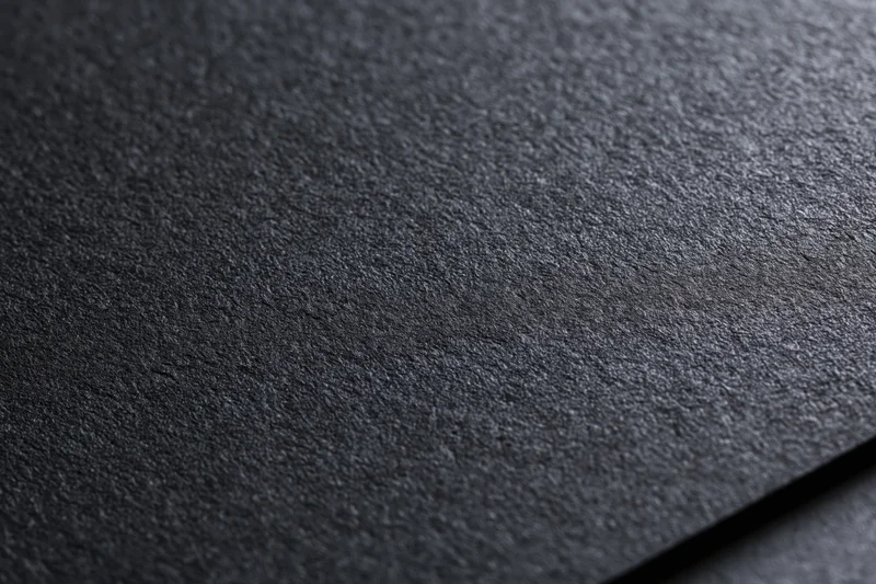 Close-up of dark black textured paper surface with visible grain and matte finish