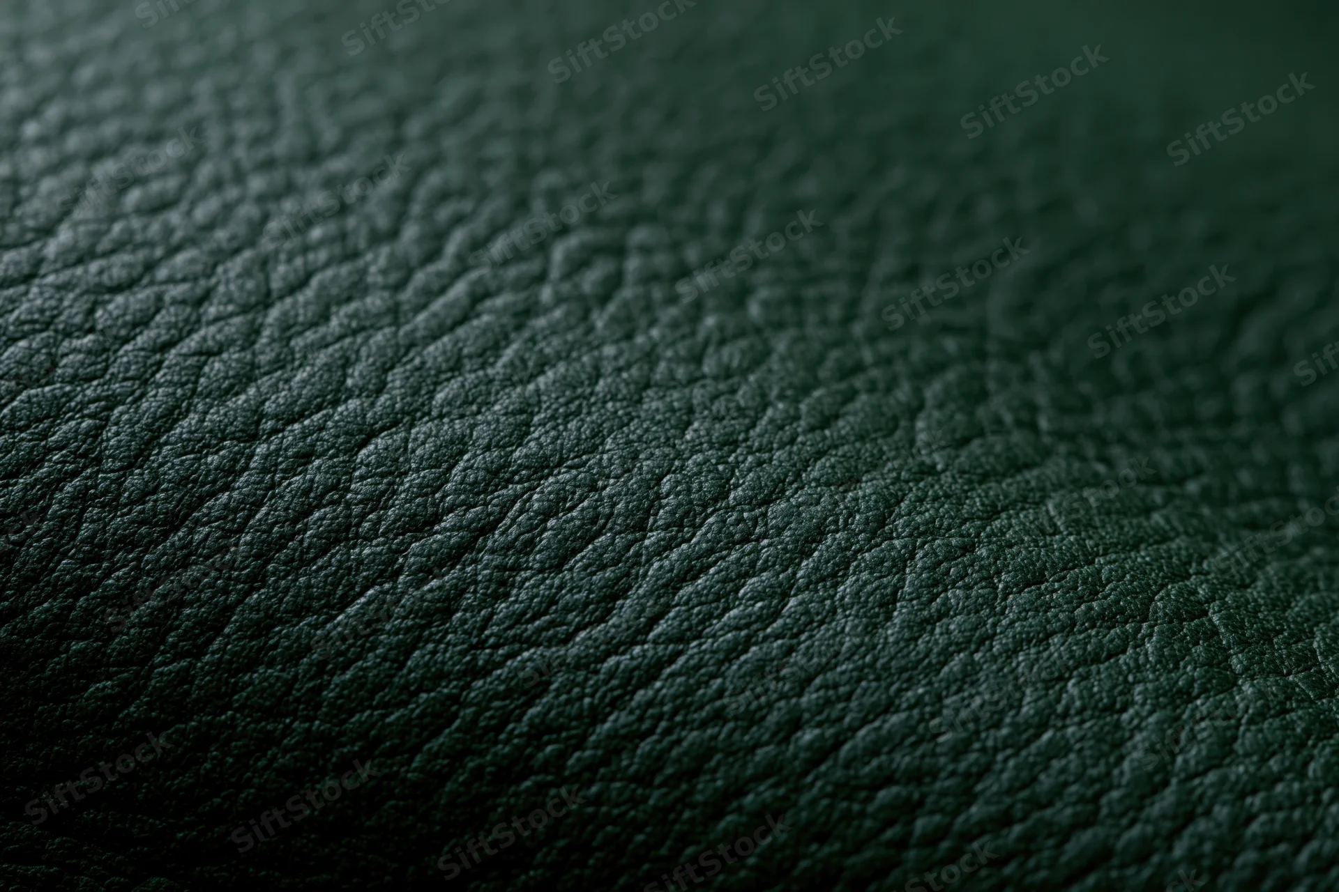 Close-up of dark forest green leather surface with pebbled texture and soft lighting
