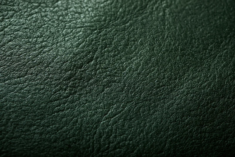 Close-up of dark forest green leather surface with visible grain and texture