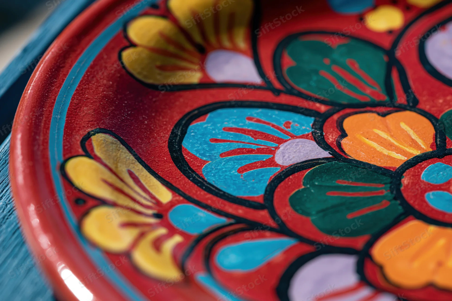 Close-up of a hand-painted mexican talavera ceramic plate with floral design in red and bright colors