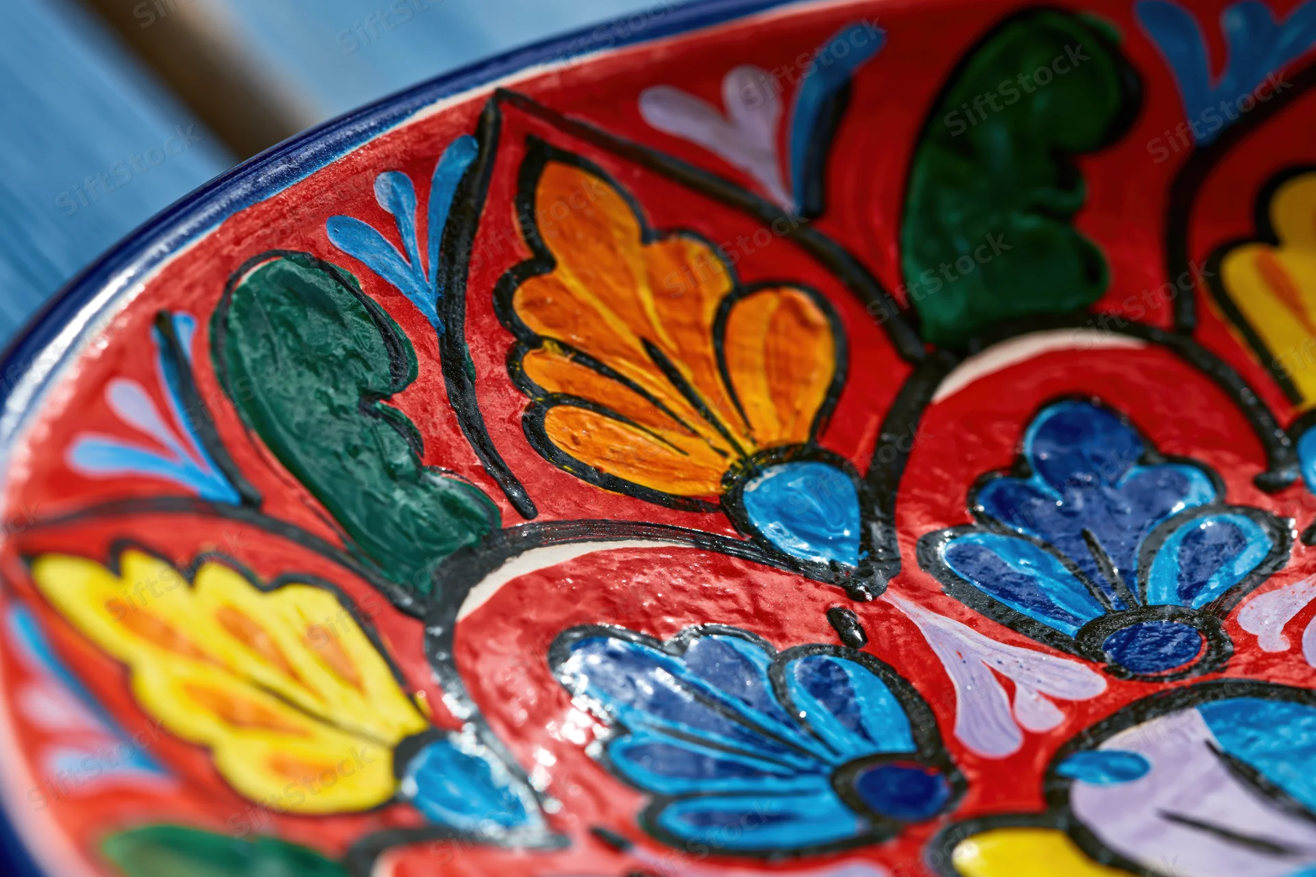 Close-up of a hand-painted mexican talavera ceramic plate with vibrant floral patterns in red blue yellow and green