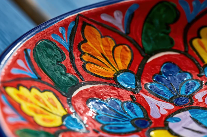 Close-up of a hand-painted mexican talavera ceramic plate with vibrant floral patterns in red blue yellow and green