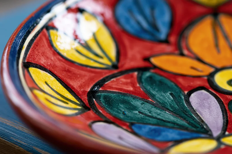 Close-up of a hand-painted mexican talavera ceramic plate with colorful floral pattern on a wooden surface