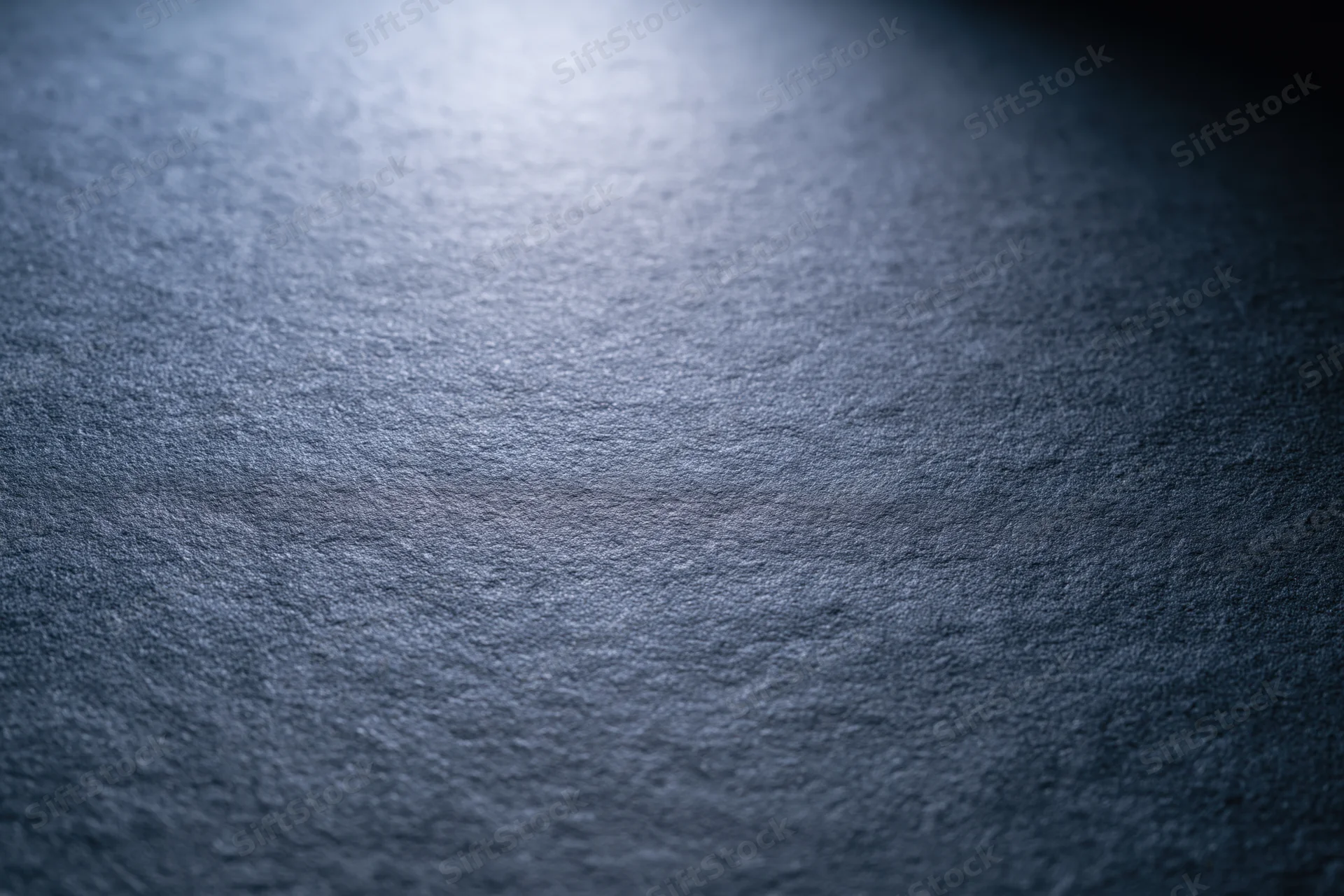Close-up of a matte dark grey textured surface in a flat lay wide shot