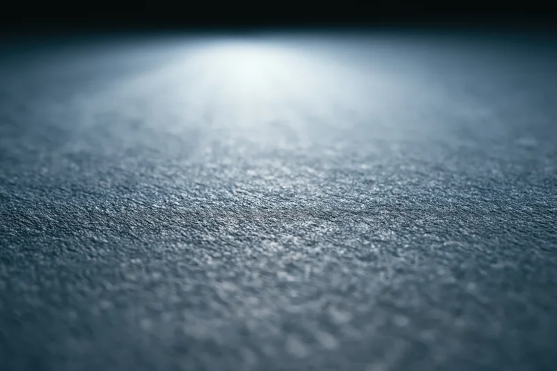 Close-up of a matte dark grey textured surface with soft lighting and shallow depth of field