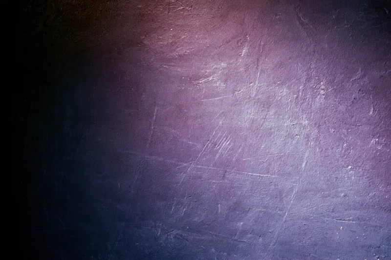 Close-up of a worn concrete wall surface with purple and blue gradient lighting