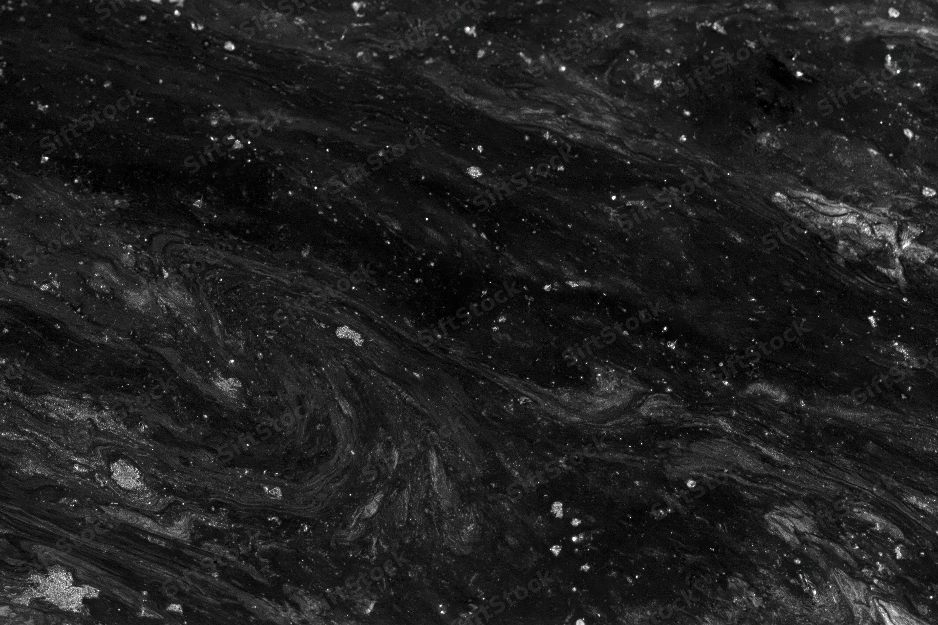 Dark oily water surface with swirling patterns and scattered speckles, overhead close-up view