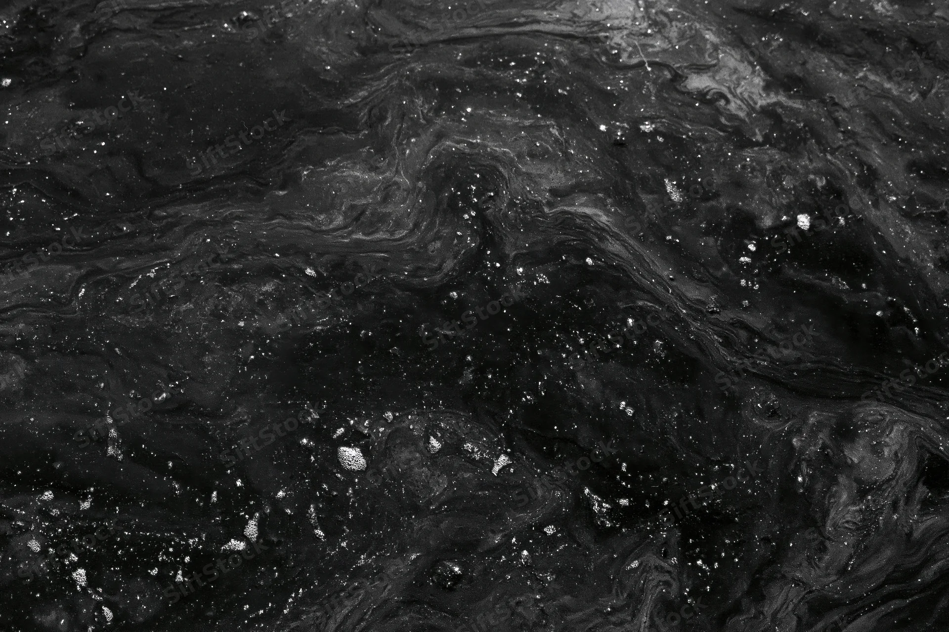 Dark oily water surface with swirling patterns and scattered bubbles