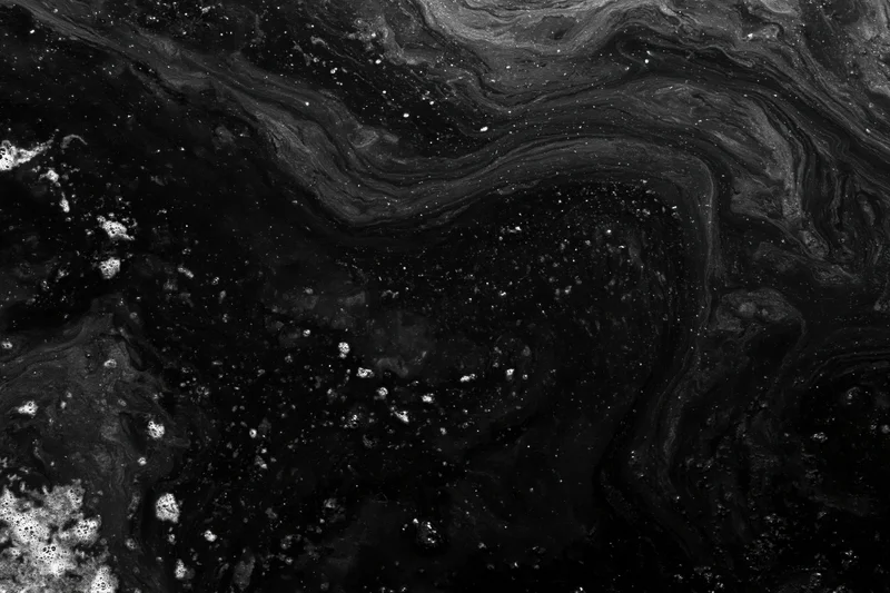 Dark oily water surface with swirling patterns and reflective sheen