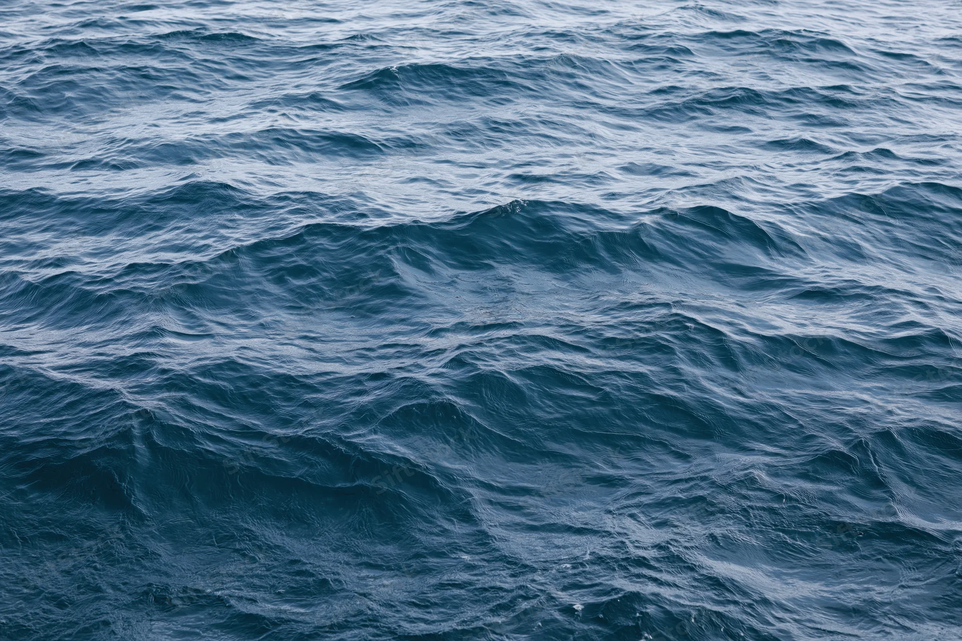 Close-up overhead view of open ocean surface with low rolling waves