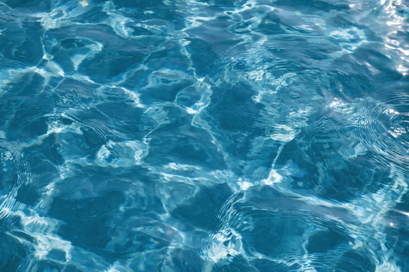 Rippling surface of clear blue pool water under sunlight