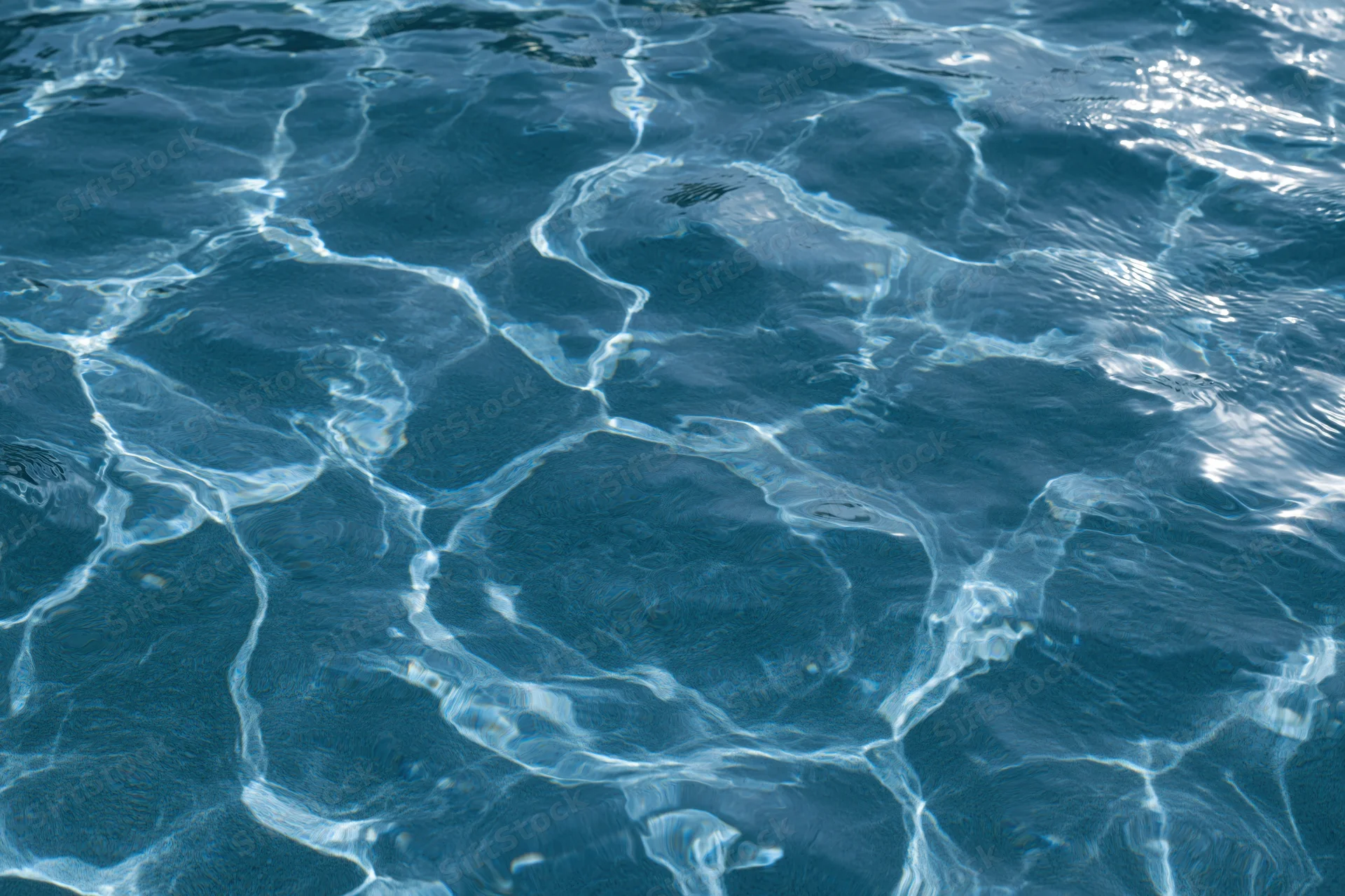 Rippling surface of clear blue pool water with light reflections and ripples