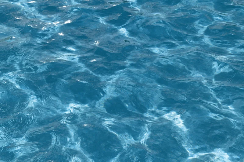 Rippling surface of pool water with light reflections and ripples
