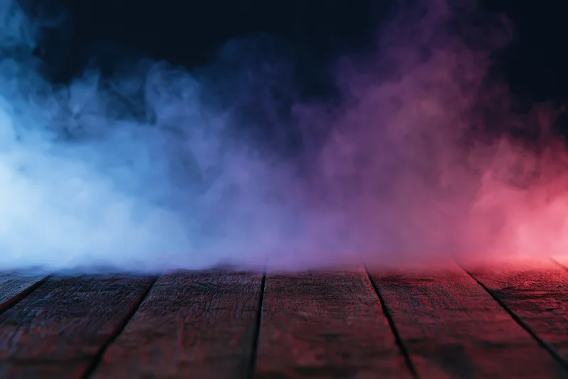 Colored smoke rising from a wooden floor in a dark space