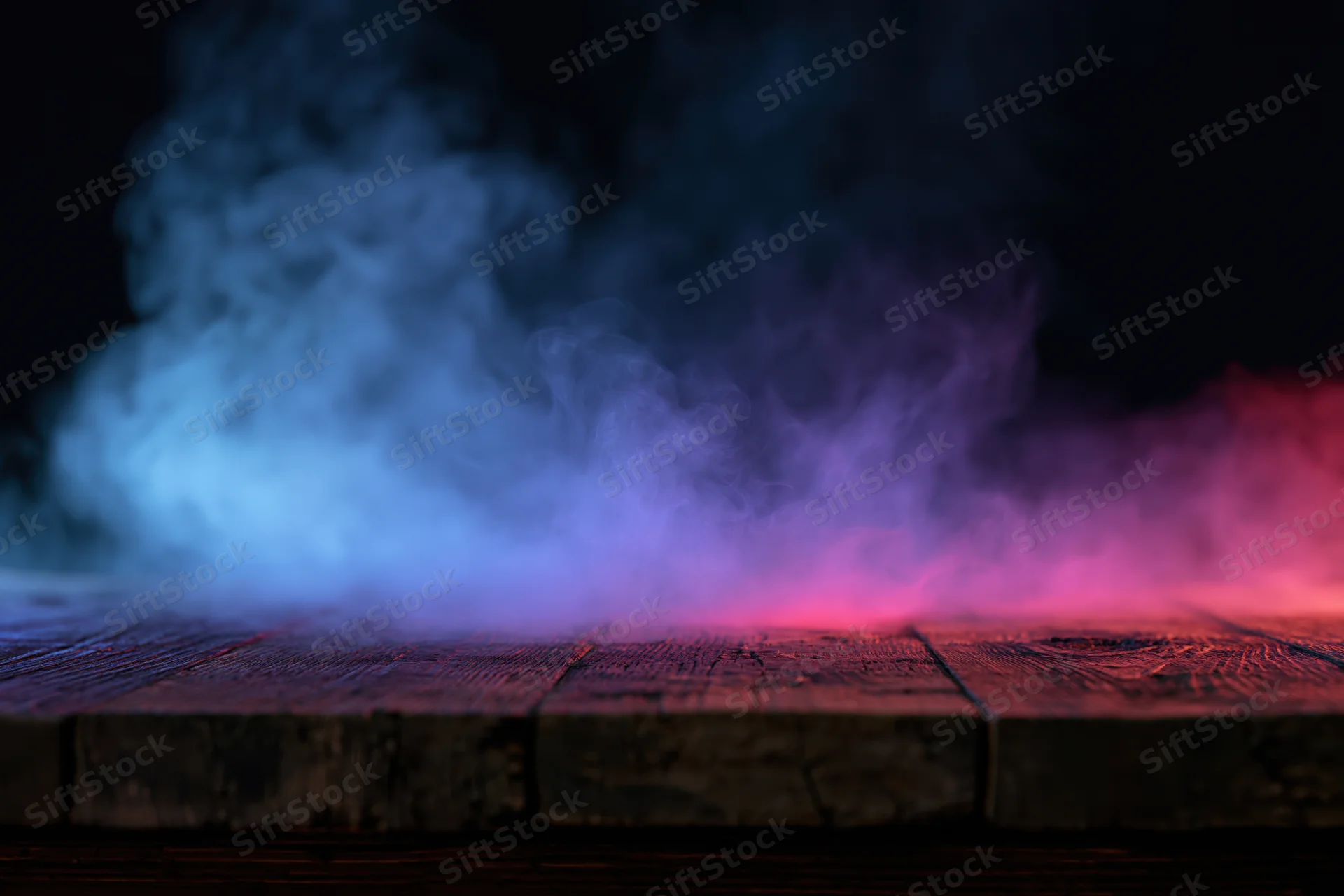 Colored smoke rising from a wooden surface in a dark setting with blue and pink lighting